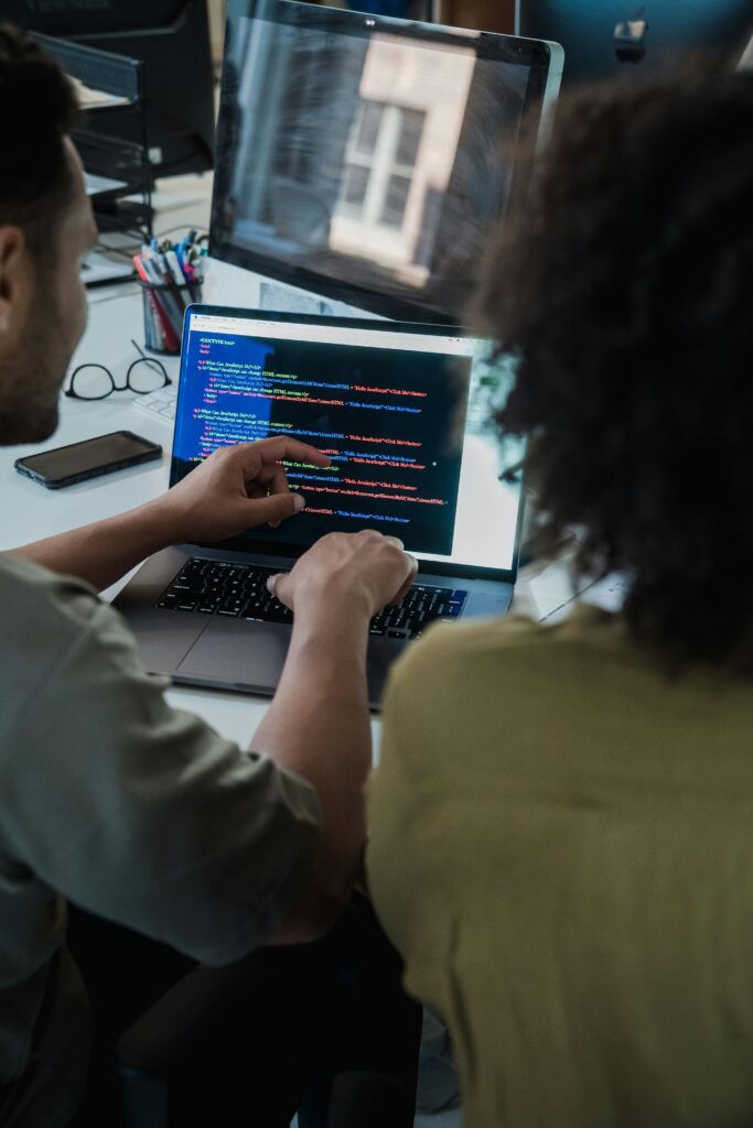 pexels photo 12899151 12899151 Two adults collaborating on programming tasks using a laptop in an office setting.