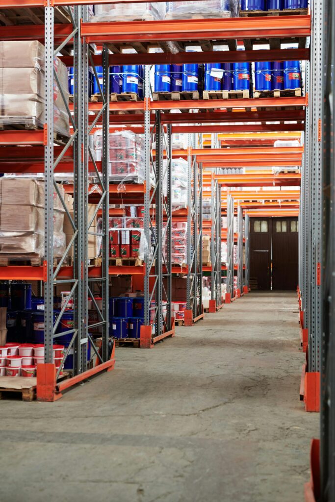 pexels photo 4483609 4483609 Industrial warehouse interior with organized shelves stacked with packages and goods.